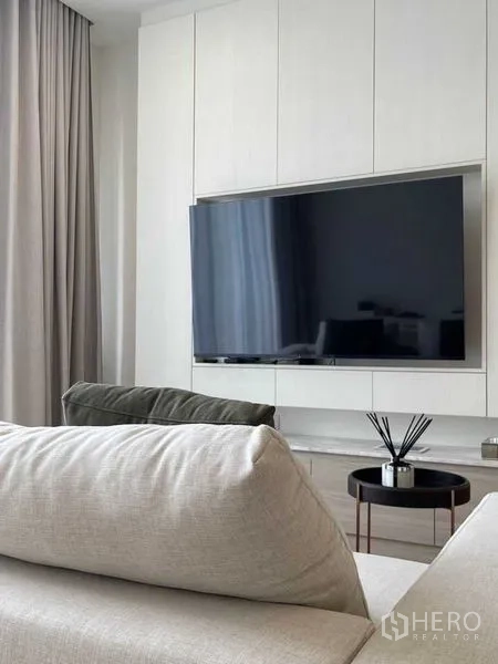 公寓 出售在Watthana, Bangkok - 电视背景墙对面是舒适转角沙发与小圆边几。