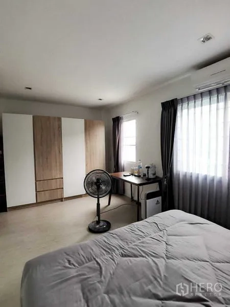 Home Office for rent or sale - Spacious bedroom with a wardrobe, study desk and windows dressed with sheer curtains.