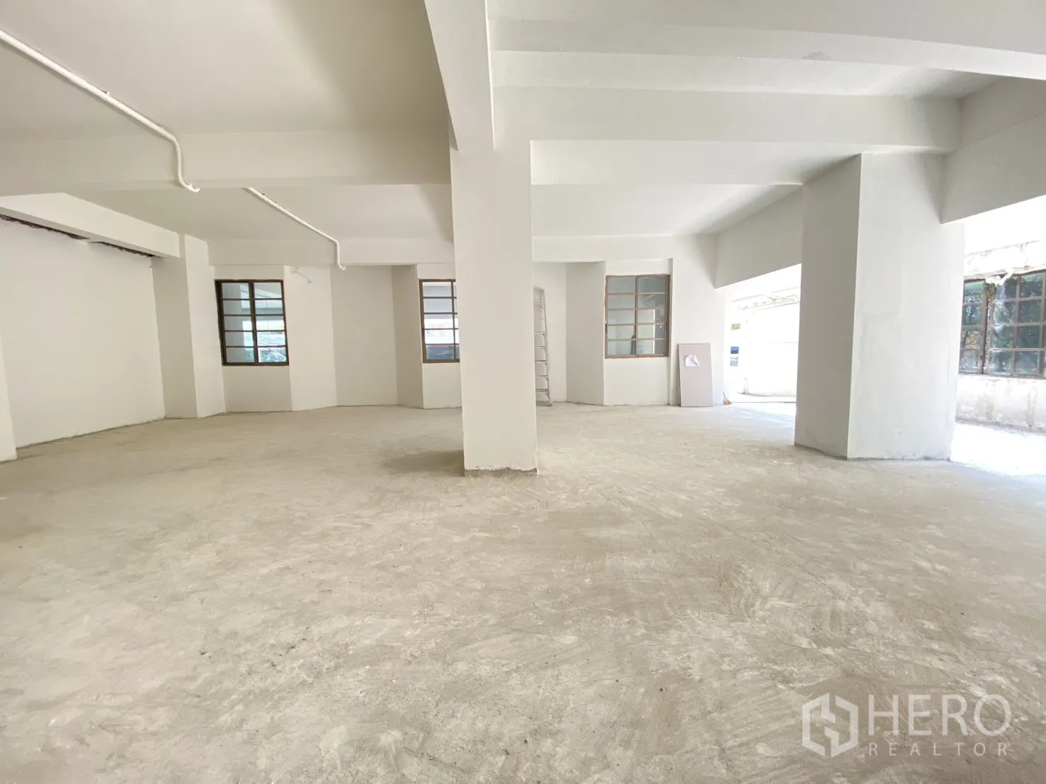 零售空间 for rent in Watthana, Bangkok - 转角区域配多窗、白色立柱与未完成水泥地。