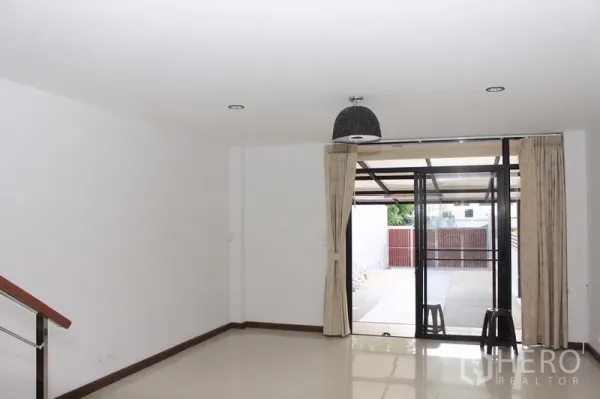 Townhouse for rent in Phaya Thai, Bangkok - Spacious ground-floor living area with glossy tile floors opening via sliding doors to a covered carport and gated front patio.