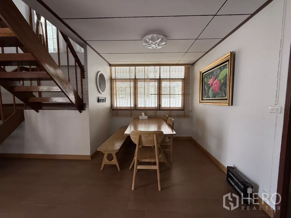 บ้าน ให้เช่าในPhra Khanong, Bangkok - มุมทานอาหารข้างบันไดไม้ มีมู่ลี่หน้าต่างและภาพแขวนผนัง.