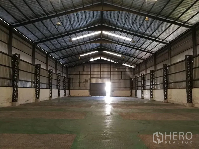 Warehouse for rent in Prawet, Bangkok - Spacious warehouse interior in Prawet, Bangkok with high gabled steel roof, polished concrete floor, and large sliding door.