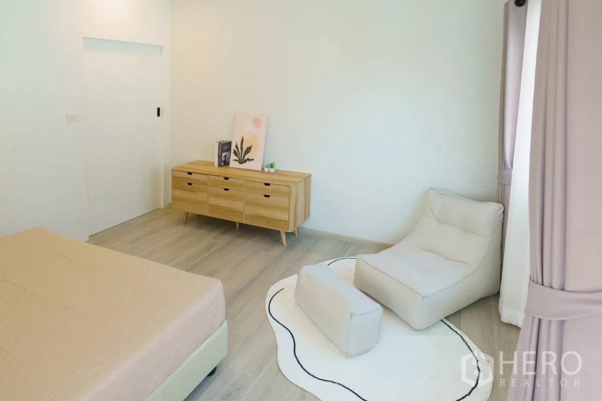 Detached House for rent in Bang Phli, Samut Prakan - Bedroom angle showing wooden sideboard and lounge seating area.