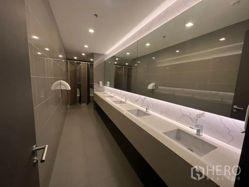 Office Space for rent - Spacious washroom with a long marble-top vanity and illuminated mirrors.