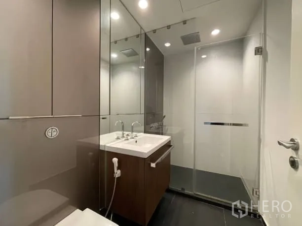 คอนโด ให้เช่าหรือขายในPathum Wan, Bangkok - ห้องน้ำสไตล์โมเดิร์นพร้อมห้องอาบน้ำกระจก อ่างล้างหน้า ตู้กระจก และไฟดาวน์ไลต์