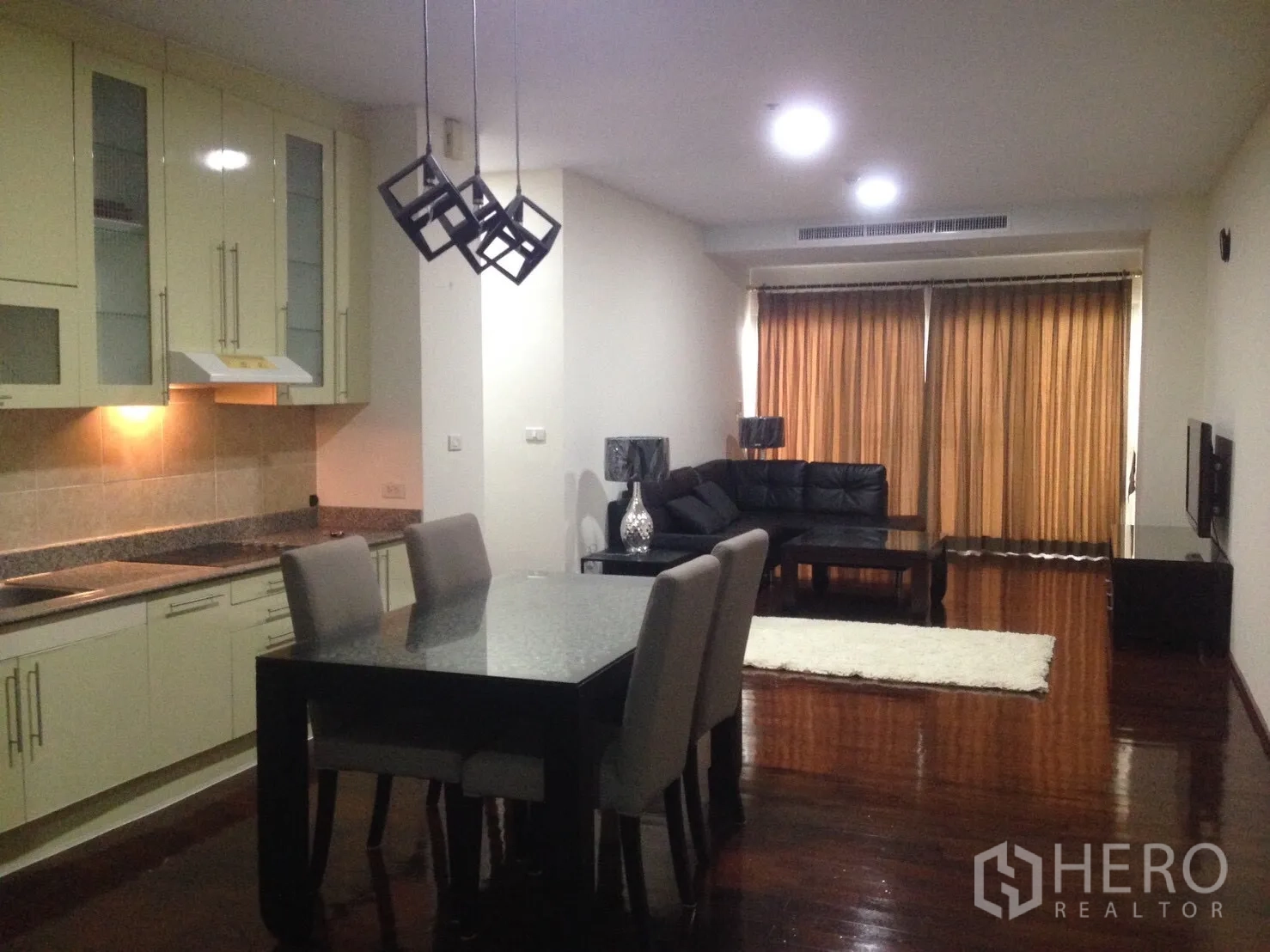 คอนโด ให้เช่าในWatthana, Bangkok - พื้นที่นั่งเล่นและทานอาหารแบบเปิดโล่ง พร้อมครัวบิลท์อิน โคมไฟ และโซฟาหนังสีดำ