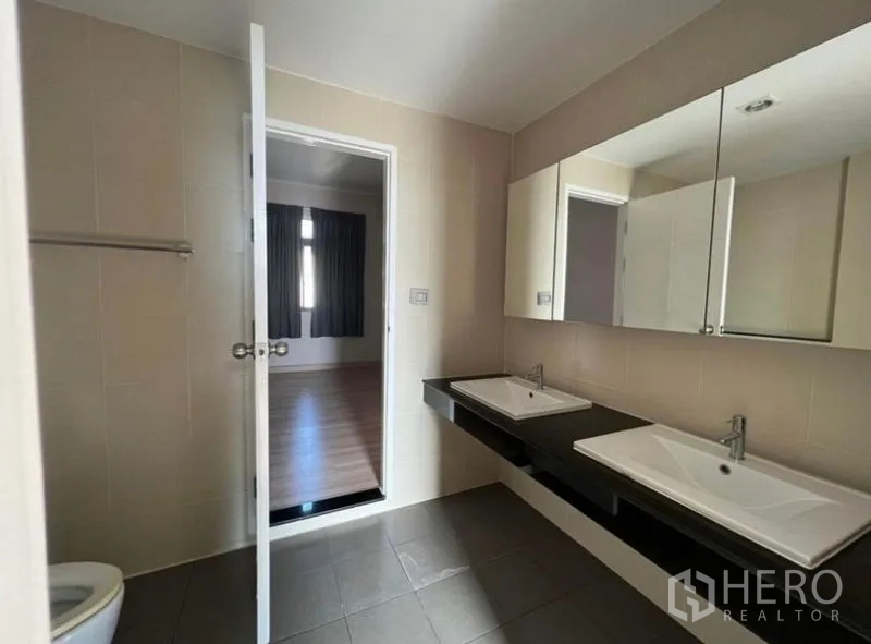 Townhouse for rent or sale in Bang Kho Laem, Bangkok - Spacious bathroom with double sinks, wide mirror cabinets and neutral tiles.