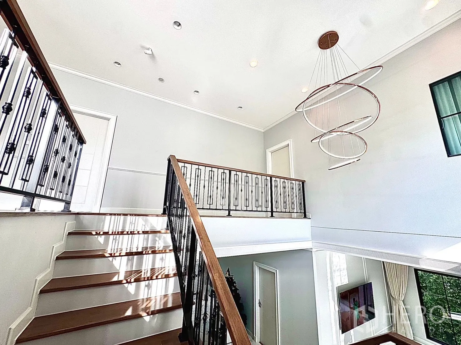 Detached House for rent in Bang Phli, Samut Prakan - Staircase with wooden treads, metal balustrade and a statement chandelier in a double-height space.