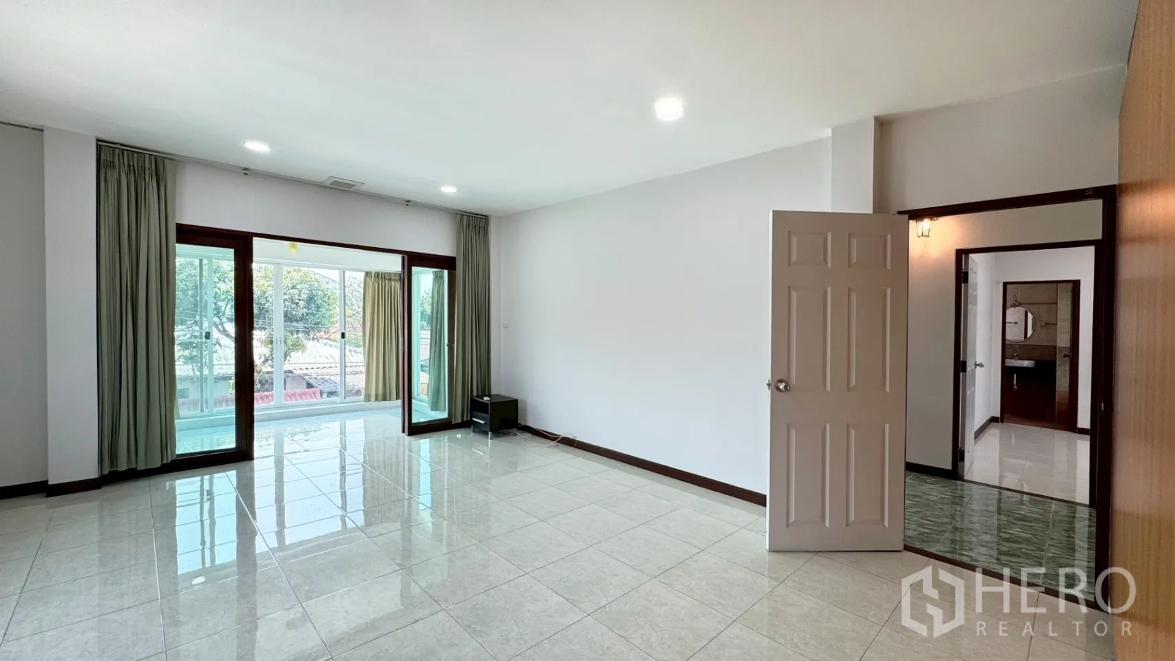 独栋房屋 for rent in Suan Luang, Bangkok - 明亮起居室，亮面地砖，推拉玻璃门连接封闭阳台。