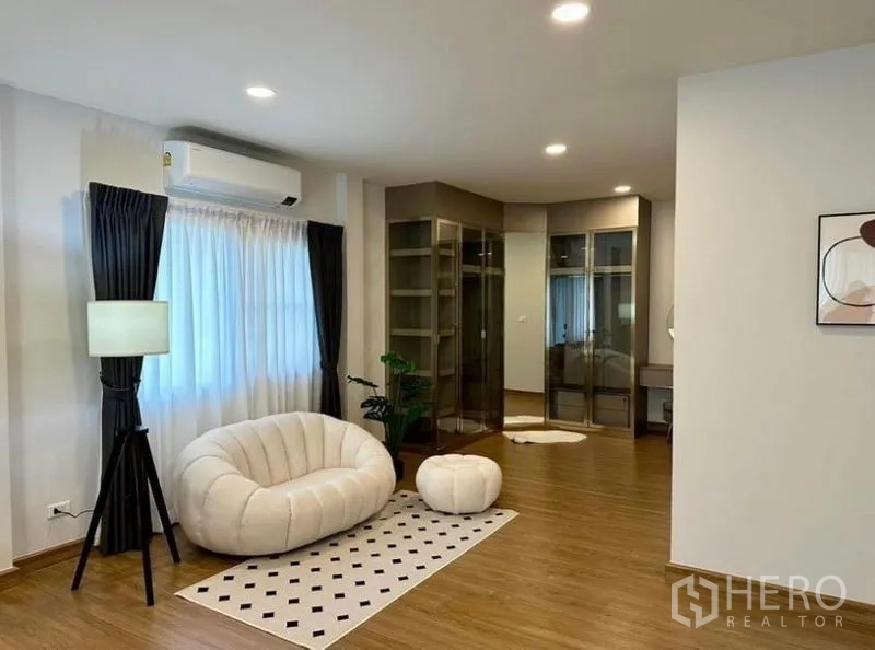 Detached House for rent in Bang Phli, Samut Prakan - Walk-in closet zone with glass wardrobes, lounge chair and warm wood flooring.