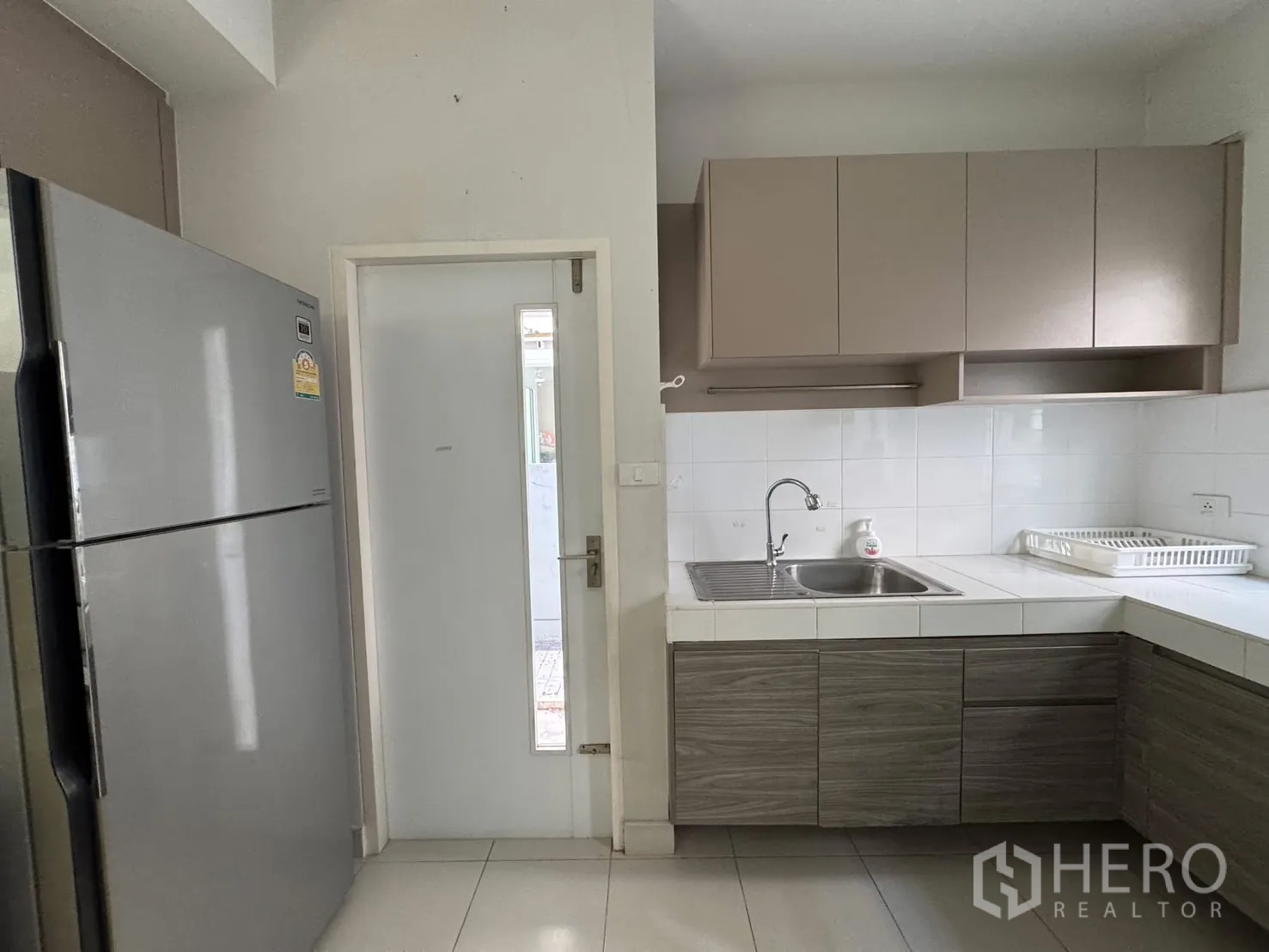 Detached House for rent in Bang Phli, Samut Prakan - Kitchen with stainless fridge, sink and upper cabinets near door.