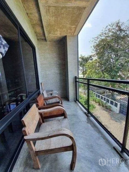 Office Space for rent or sale in Lak Si, Bangkok - Covered balcony with mesh railing and wooden chairs facing a green outlook.