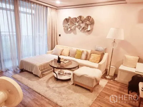 公寓 出售在Bang Rak, Bangkok - 起居区配沙发与脚凳，长窗帘与推拉门通向阳台。