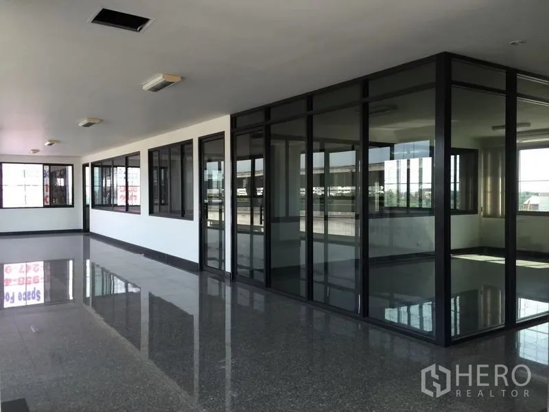 Standalone for rent in Bang Phli, Samut Prakan - Corner office area featuring full-height glass meeting rooms with dark aluminum frames.