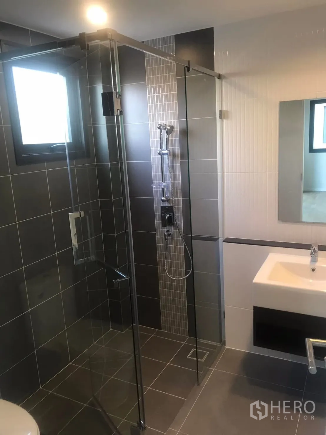 Semi-detached House for rent in Saphan Sung, Bangkok - Bathroom with glass-enclosed shower, vanity and mirror, and a window for ventilation.