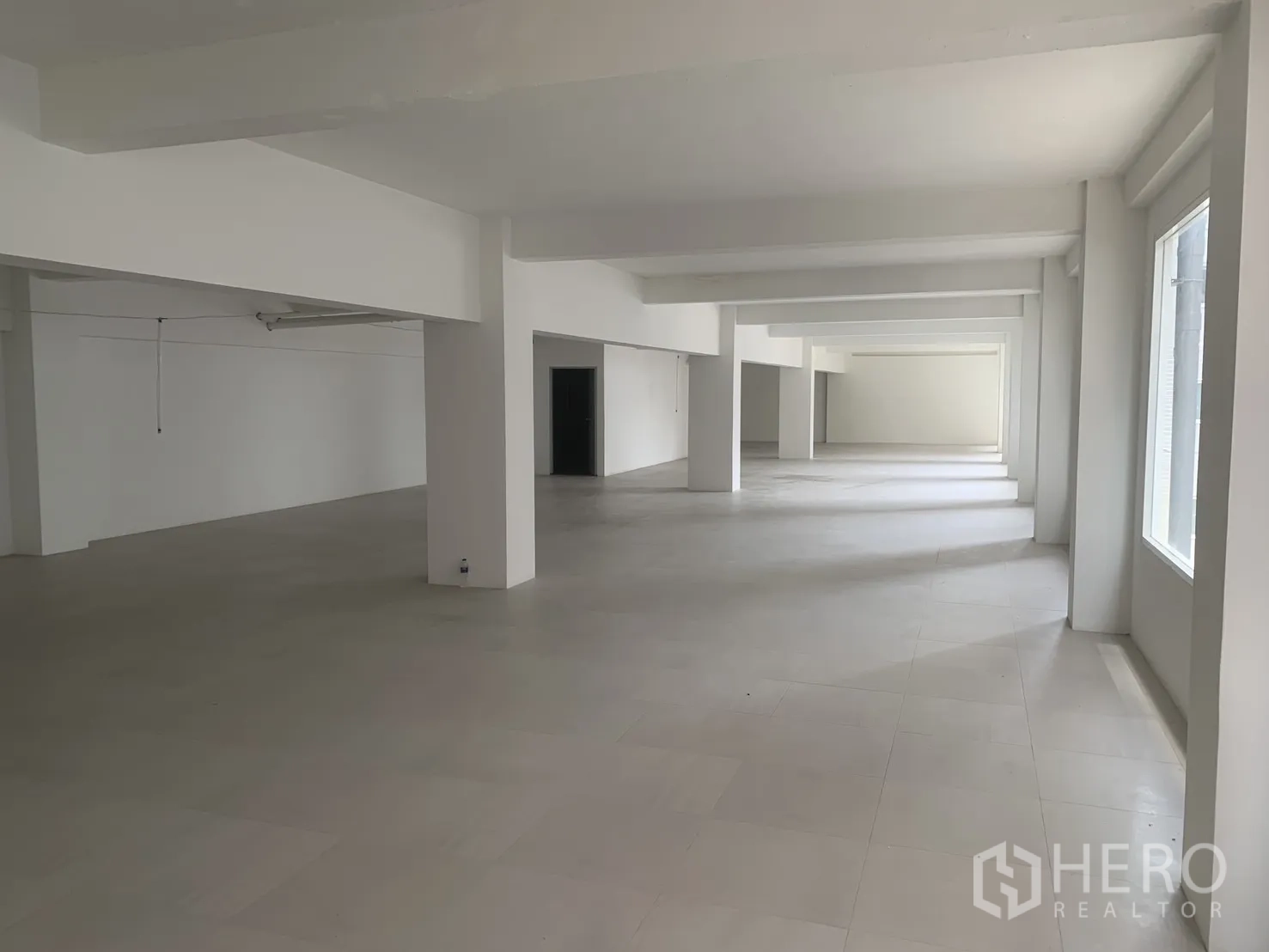 零售空间 for rent in Bang Rak, Bangkok - 宽敞开放式零售楼层，白色立柱、瓷砖地面与一排采光窗。