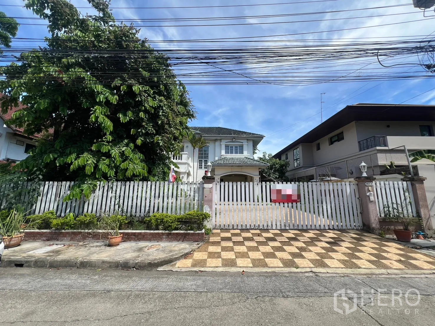 Detached House for sale in Saphan Sung, Bangkok - Street view of the property with white gate and checker-tiled driveway.