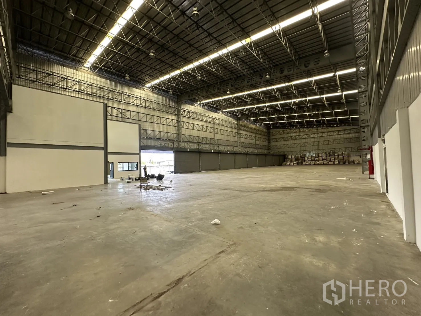 Warehouse for rent in Lat Krabang, Bangkok - Wide interior view toward shuttered bays and stacked goods at the far end.