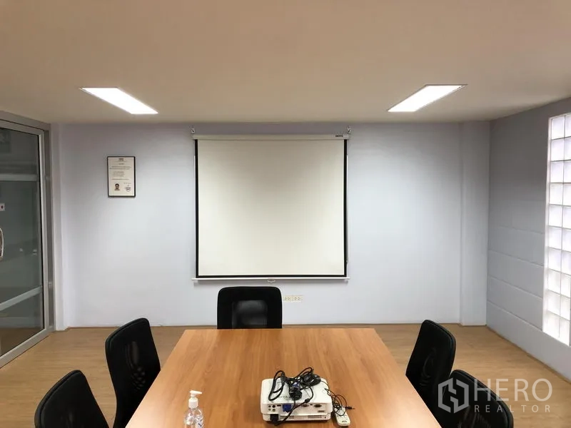 Factory for sale in Pathum Thani - Meeting room wall with pull‑down projection screen and ceiling lights.