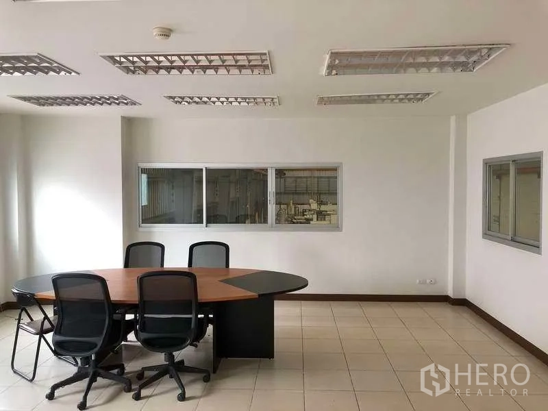 工厂 出租在Bang Sao Thong, Samut Prakan - 明亮会议室，圆形会议桌，可俯瞰生产区。