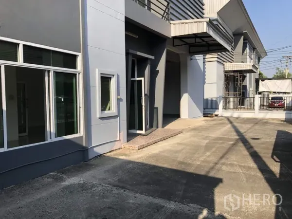 工厂 出租在Lam Luk Ka, Pathum Thani - 前院车道与玻璃门办公入口，紧邻装卸雨棚。
