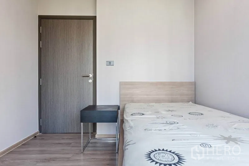 Condominium for rent or sale in Watthana, Bangkok - Compact second bedroom with single bed, bedside table and wood door.