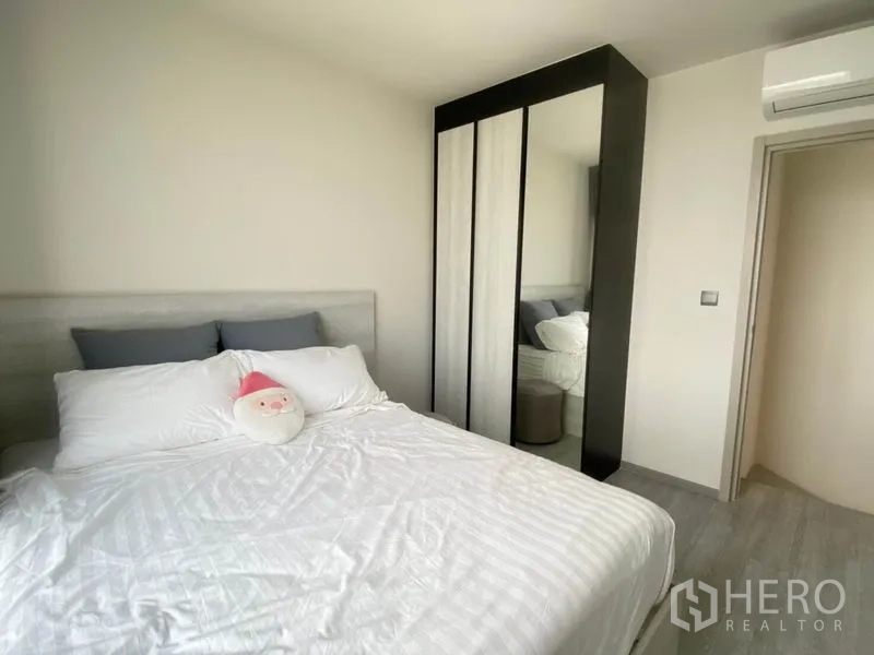 Condominium for rent in Phra Khanong, Bangkok - Bedroom corner with sliding-door wardrobe and wall-mounted air conditioner.