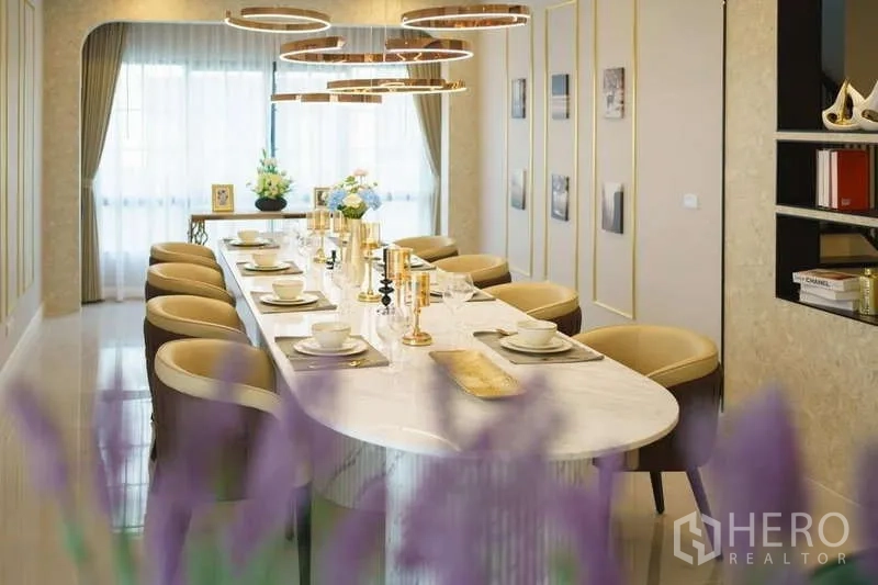 Detached House for rent or sale in Bang Phli, Samut Prakan - Elegant dining room with a long marble table, gold ring pendant lights and floor-to-ceiling curtains.