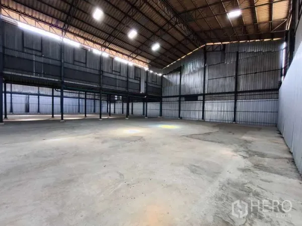 Warehouse for rent in Krathum Baen, Samut Sakhon - Spacious warehouse interior with high ceiling, steel columns, skylights, and smooth concrete floor.