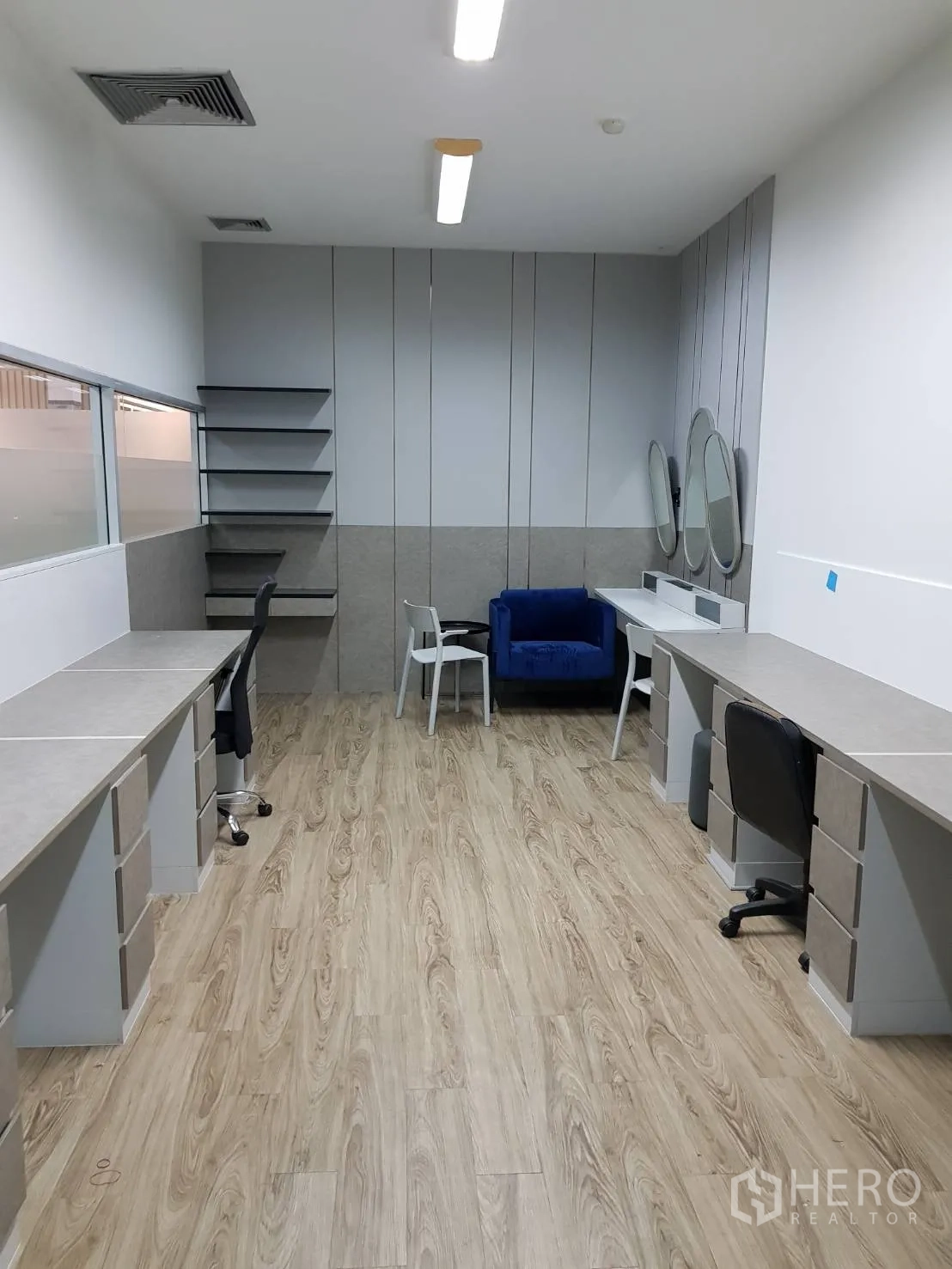 สำนักงาน ให้เช่าในKhlong Toei, Bangkok - ห้องทำงานมีโต๊ะบิวท์อินสองฝั่ง ชั้นวาง กระจกกลม และโซฟาสีฟ้าใต้ไฟเพดาน