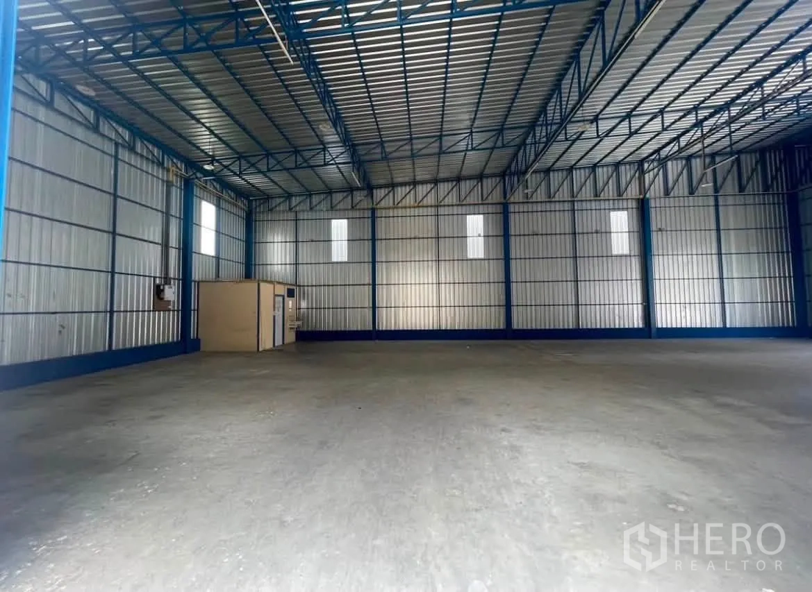 Warehouse for rent in Wang Thonglang, Bangkok - Warehouse interior showing the entry area and wide concrete floor beneath a metal roof.