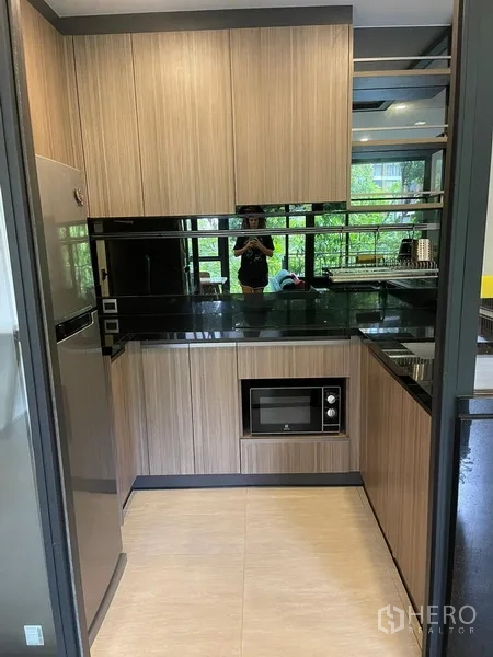 Condominium for rent in Watthana, Bangkok - Full view of enclosed kitchen with fridge and microwave, mirrored splashback.