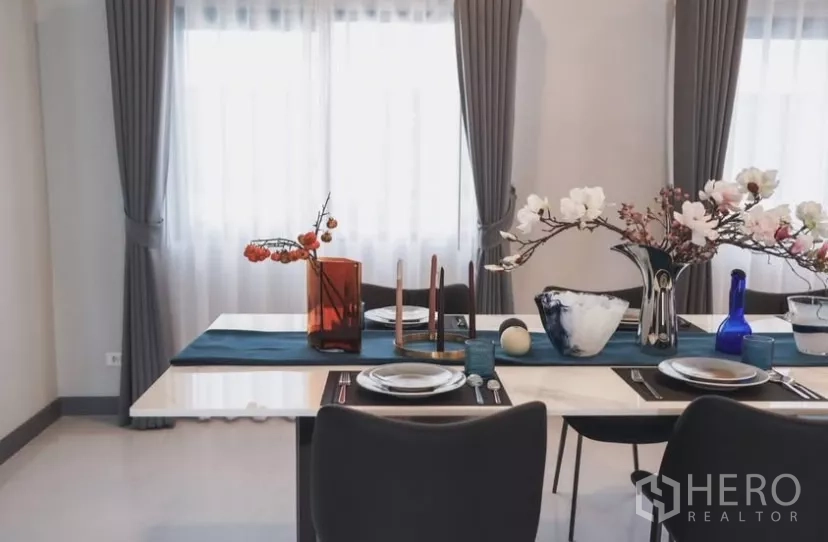 Detached House for rent in Bang Phli, Samut Prakan - Elegant dining table set with tableware and floral centerpieces by draped windows.