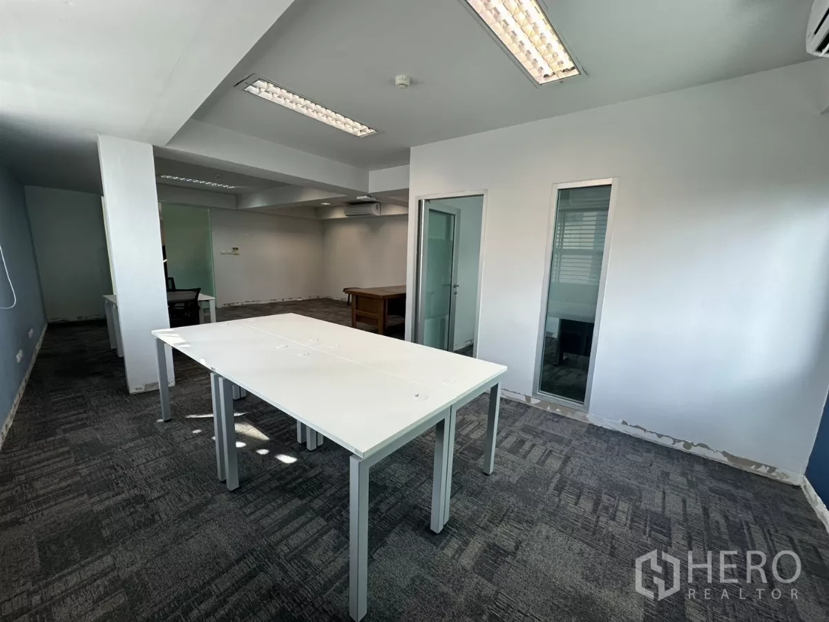 Office Space for rent in Watthana, Bangkok - Bright open workspace with white worktables, glass partitions and overhead fluorescent lighting.
