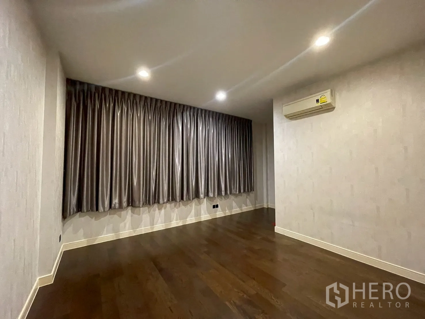 Detached House for rent in Bang Kapi, Bangkok - Air-conditioned bedroom with dark curtains and polished wood flooring.