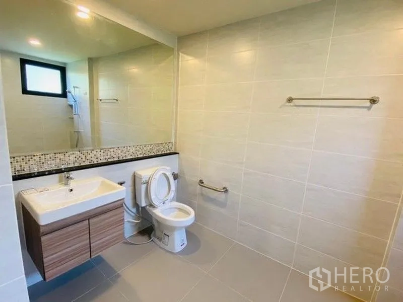 Detached House for sale in Bang Phli, Samut Prakan - Spacious tiled bathroom with floating vanity, large wall mirror and toilet.