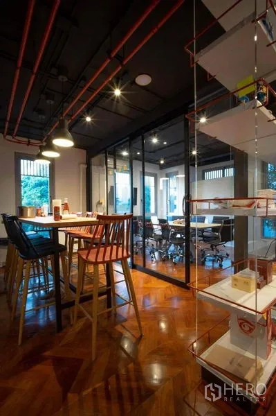 Office Space for rent in Khlong Toei, Bangkok - Breakout area with a high table and stools beside a glass-walled meeting room.