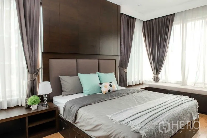 คอนโด ให้เช่าหรือขายในBangkok - ห้องนอนหลัก ผนังหัวเตียงไม้เข้ม พร้อมที่นั่งริมหน้าต่าง