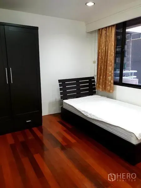 公寓 出租或出售在Watthana, Bangkok - 紧凑卧室，单人床、黑色衣柜与打蜡木地板。