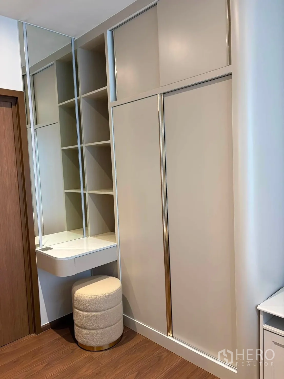 Condominium for rent in Watthana, Bangkok - Bedroom corner with sliding wardrobe, mirrored dressing table, and cushioned stool.