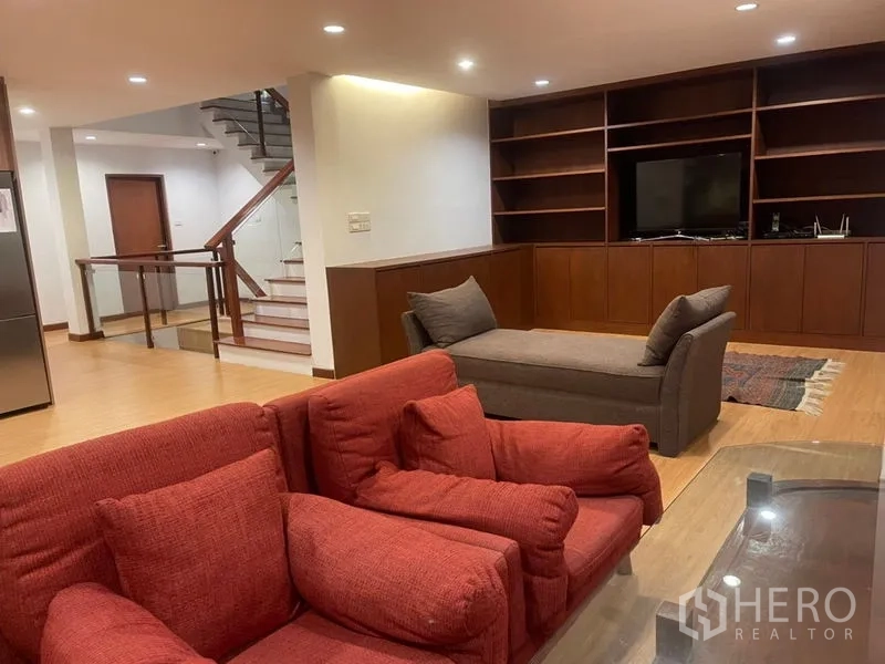 ทาวน์เฮาส์ ให้เช่าในSuan Luang, Bangkok - ห้องนั่งเล่นกว้าง พร้อมชั้นวางบิลท์อิน ผนังทีวี พื้นไม้ และบันไดภายใน