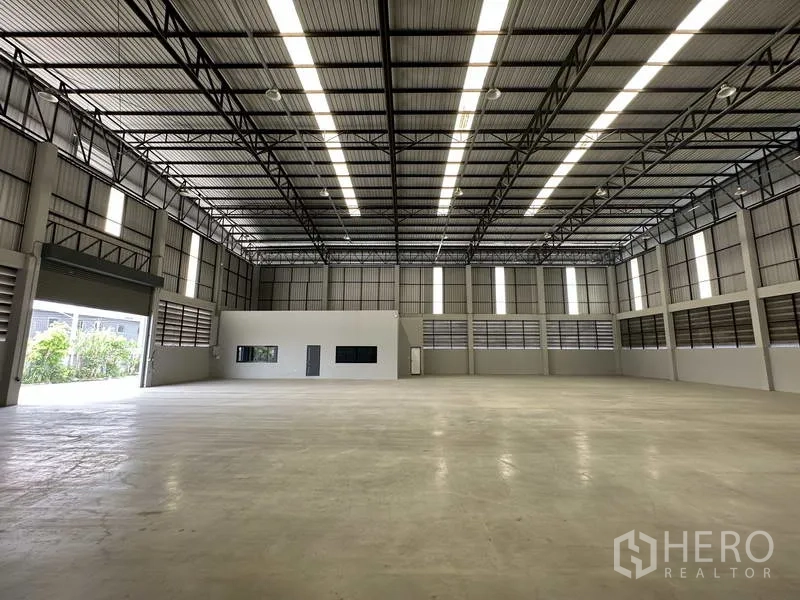 货栈 出租在Bang Phli, Samut Prakan - 仓库大厅，侧边设有卷帘门与内部办公室。
