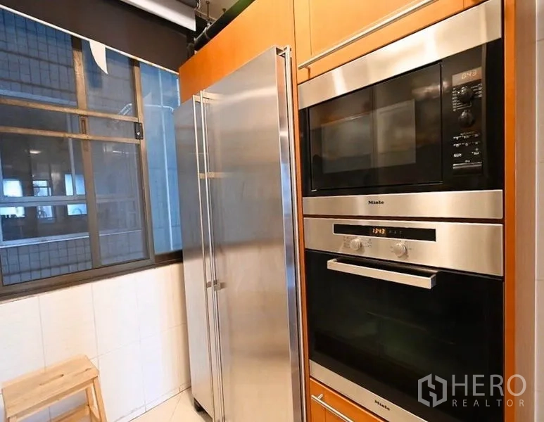 Condominium for rent in Pathum Wan, Bangkok - Built-in Miele oven and microwave next to a large stainless side-by-side refrigerator.