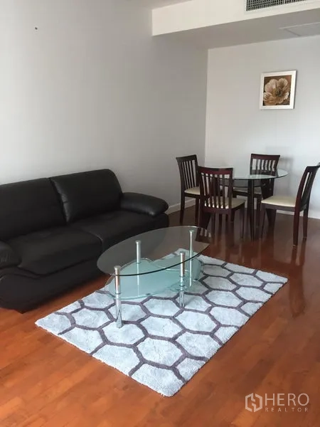 คอนโด ให้เช่าในKhlong Toei, Bangkok - โถงนั่งเล่นแบบเปิดโล่ง โซฟาหนัง โต๊ะกลางกระจก พรม และชุดทานอาหารกลมบนพื้นไม้