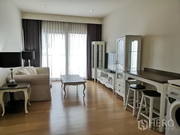 Condominium for rent or sale in Phaya Thai, Bangkok - Open-plan living room with sofa, TV cabinet and tall glass doors to the balcony.