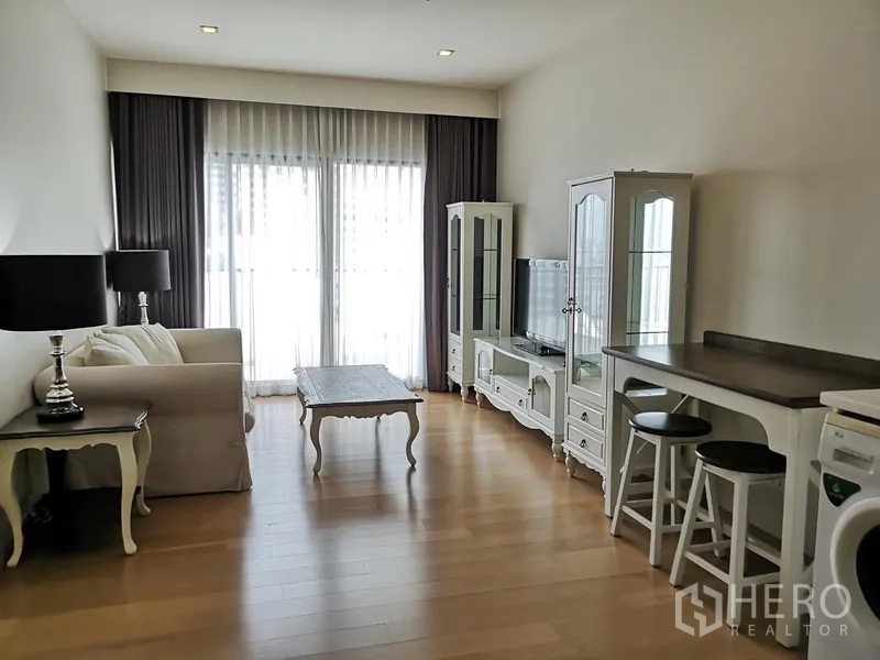 Condominium for rent or sale in Phaya Thai, Bangkok - Open-plan living room with sofa, TV cabinet and tall glass doors to the balcony.