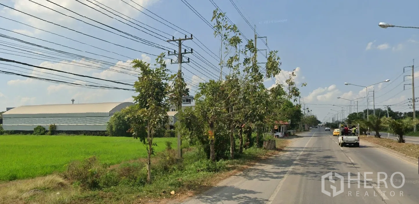 Land for sale in Lat Lum Kaeo, Pathum Thani - Perspective along the highway past the site, with vehicles, street lighting and electrical poles.