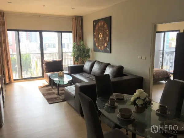 คอนโด ให้เช่าในWatthana, Bangkok - ห้องนั่งเล่นและรับประทานอาหารแบบโอเพนแปลน โซฟาหนัง โต๊ะกระจก และหน้าต่างบานใหญ่เปิดรับวิวเมือง