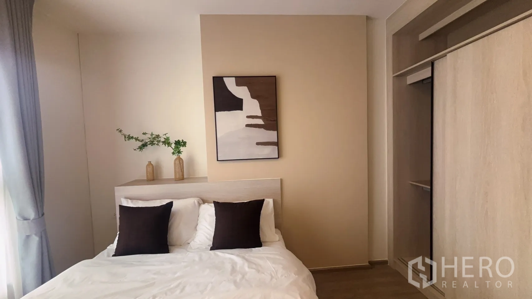 Condominium for rent in Watthana, Bangkok - Second angle of the bedroom with bed, decorative vases, artwork, and built-in sliding wardrobe.