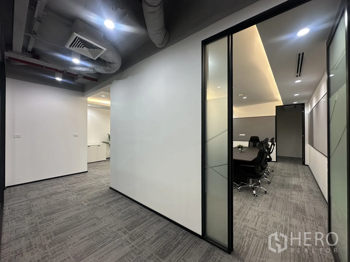 办公室 for rent in Pathum Wan, Bangkok - 走廊带外露管道天花，通向灯光柔和的会议室。